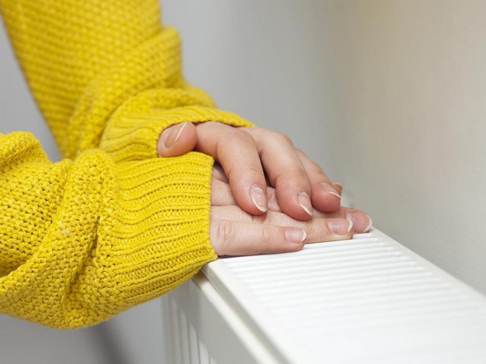 woman-warms-her-hands-radiator